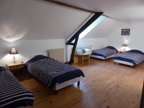 Cette chambre mansardée comprend 3 lits et une fenêtre. dans l'établissement Le Domaine des Tostes, à Bonneville-la-Louvet