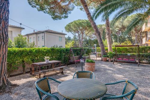 a patio with a table and chairs and trees at Hotel Massimo in Marina di Cecina