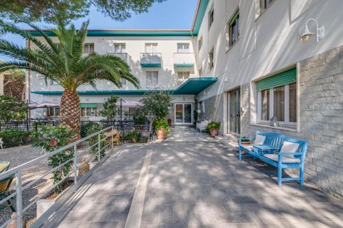 un balcón de un edificio con un banco azul y una palmera en Hotel Massimo, en Marina di Cecina