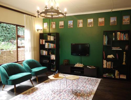 Claires of Sandton Luxury Guest House في جوهانسبرغ: غرفة معيشة خضراء مع كرسيين وتلفزيون