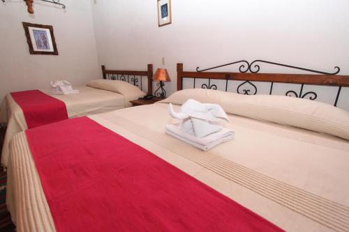 dwa łóżka w pokoju z czerwono-białym w obiekcie Parador Monte Carmelo w mieście Oaxaca