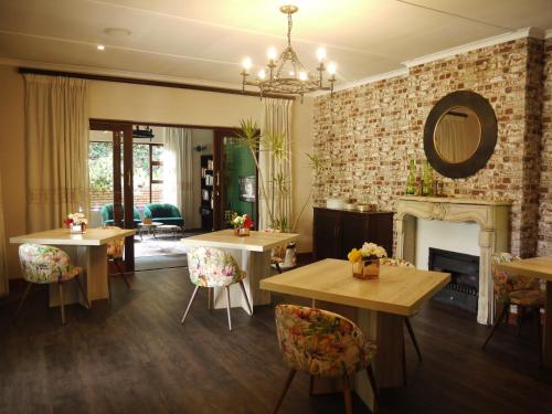 a living room with tables and chairs and a fireplace at Claires of Sandton Luxury Guest House in Johannesburg