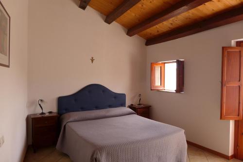 um quarto com uma cama azul e uma janela em La Suma Sumalia em Noto