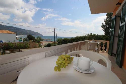 a white table with a cup and grapes on it at House Dimitri Agios Georgios Pagoi Corfu in Agios Georgios Pagon