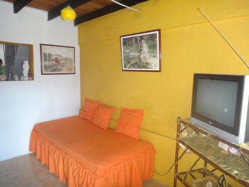 ein gelbes Zimmer mit einem Bett und einem Fernseher in der Unterkunft Green Sea Villa Helen Inn - Kilometer 4 Circunvalar in Buenavista