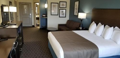 a hotel room with a large bed and a couch at AmericInn by Wyndham Sioux Falls North in Sioux Falls