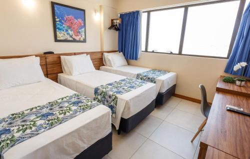 a hotel room with three beds and a window at Rede Andrade Riviera Premium in Salvador