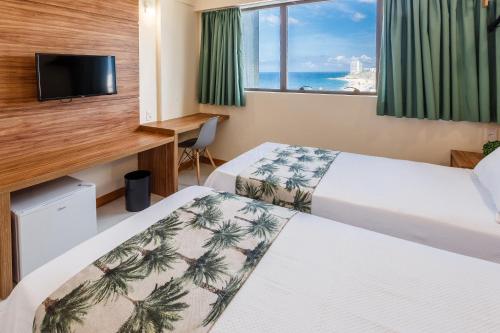 um quarto de hotel com duas camas e uma janela em Rede Andrade Riviera Premium em Salvador