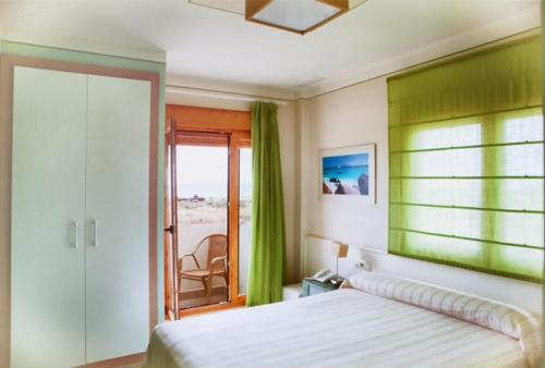 1 dormitorio con 1 cama y puerta corredera de cristal en Colores de Zahara, en Zahara de los Atunes