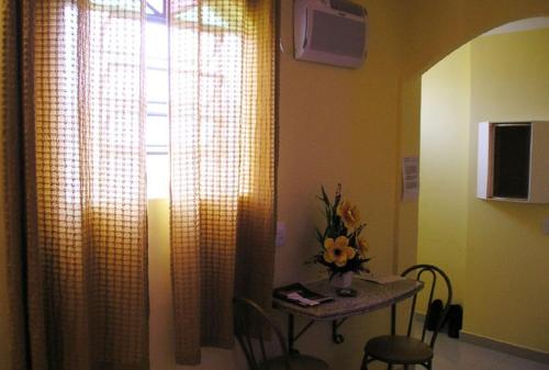 a table with a vase of flowers and a table with a window at MOTEL RED LOVE in Belo Horizonte