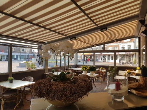 a restaurant with tables and chairs and windows at De Eenhoorn in Oostburg
