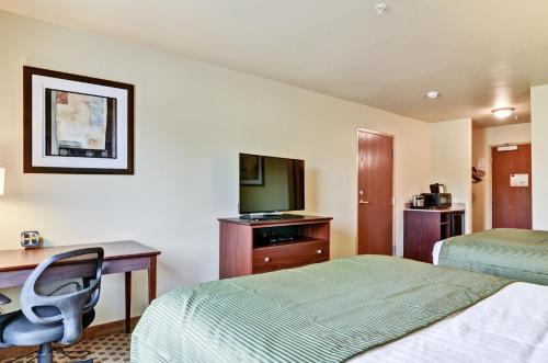 a hotel room with two beds and a desk and a television at Castle Rock Inn & Suites - Quinter in Quinter