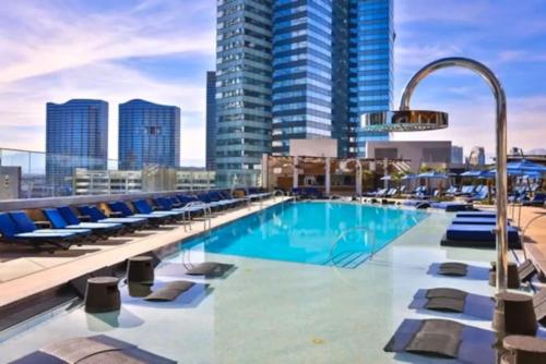 a pool on the roof of a building with chairs and buildings at Stay Together Suites - Spacious Condominium On The Strip Sleeps 12 - NO RESORT FEE in Las Vegas