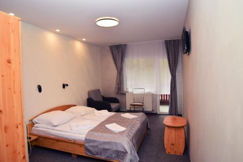 ein kleines Schlafzimmer mit einem Bett und einem Stuhl in der Unterkunft Pensiunea Arinul in Sovata