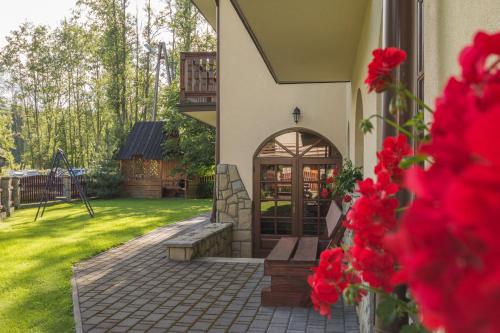 drzwi wejściowe domu z czerwonymi kwiatami w obiekcie Dom Wczasowy Na Kamieńcu w mieście Białka Tatrzanska