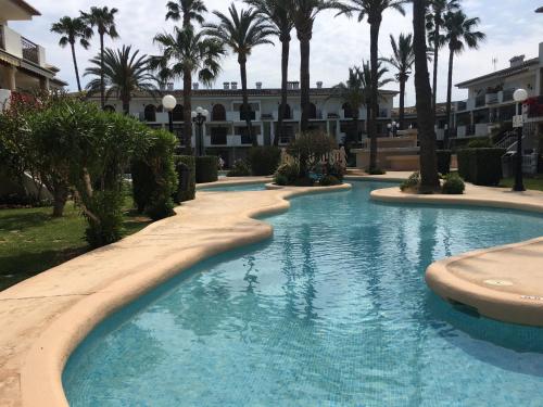 a swimming pool in a resort with palm trees at Frente al Mar. Atlantic in Denia