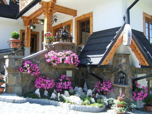 a house with a bunch of flowers in front of it at Pensjonat Zbójecki Dwór - ATRAKCYJNY PAKIET ŚWIĄTECZNY - blisko basenów termalnych i szlaków górskich in Bukowina Tatrzańska