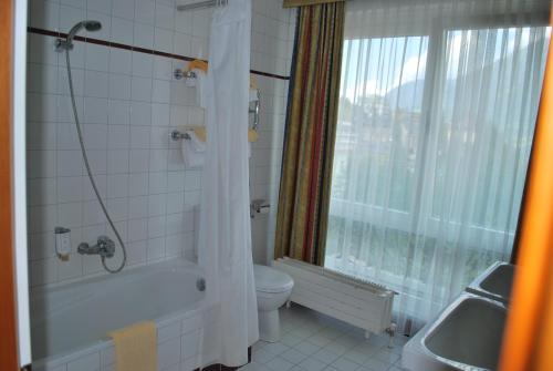 a bathroom with a tub and a toilet and a window at Thermal Resort Hotel Elisabethpark in Bad Gastein