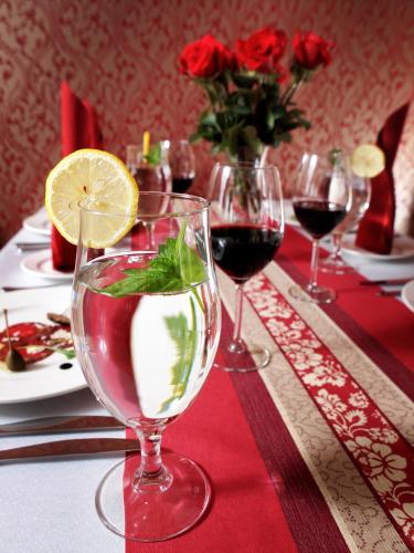 a table with wine glasses on a table with roses at Hotel Austeria Conference & Spa in Ciechocinek