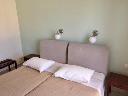 a bed with two pillows and two lights above it at Hotel Papasotiriou in Galatas