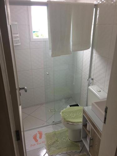 a white bathroom with a shower and a toilet at Pousada Rosa Norte in Tramandaí