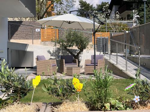 a garden with chairs and an umbrella and flowers at Apartment Zielspitz in Parcines