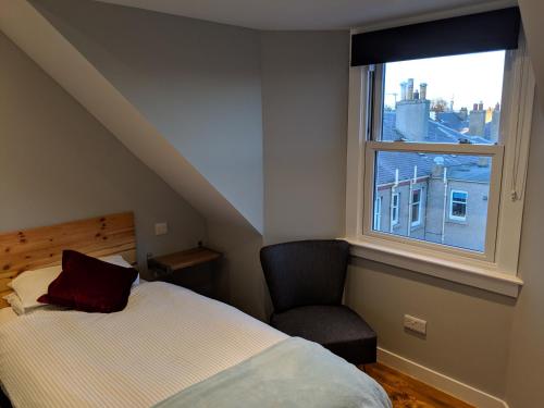 a bedroom with a bed and a chair and a window at Falcon Crest Guest House in Edinburgh