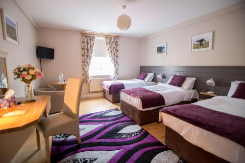 a hotel room with three beds and a table at The Ritz House in Lisdoonvarna