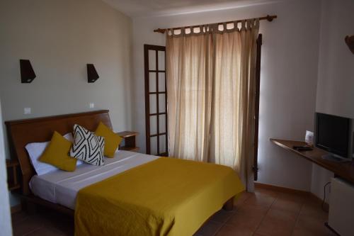 a bedroom with a bed with yellow sheets and a television at Guest House Orquidea in Sal Rei
