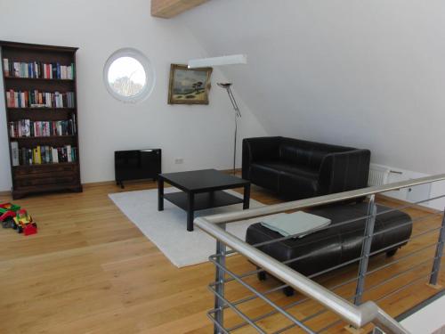 a living room with a black leather couch and a table at Ferienhaus Struckmann am Steinhuder Meer in Neustadt am Rübenberge