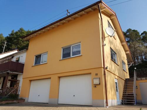 a yellow house with two garage doors at Höllenbergblick in Spirkelbach