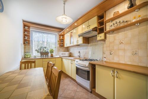 a kitchen with yellow cabinets and a table with chairs at Apartament Litoral Jurata in Jurata