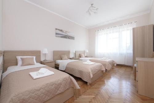two beds in a bedroom with white walls and wood floors at Apartamenty Mirada in Gdynia