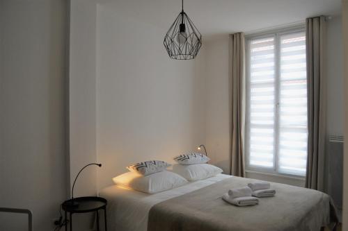 Un dormitorio blanco con una cama con toallas. en LE VOLTAIRE COLMAR CENTRE en Colmar