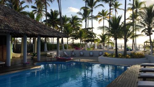 una piscina in un resort con palme di VILLA NACRI NA PRAIA con PISCINA ENTRE ILHEUS E ITACARE' a Ilhéus