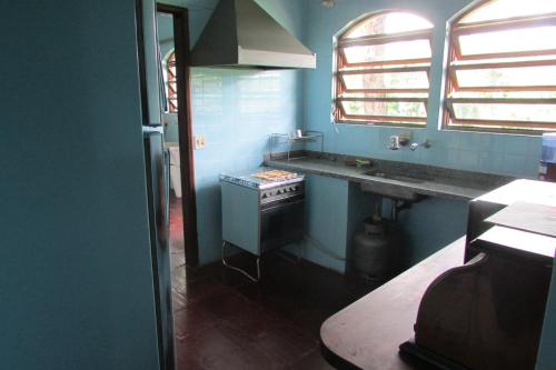 a blue kitchen with a stove and a sink at Sitio Prainha in Guararema