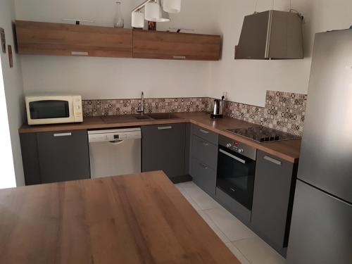 une cuisine avec des placards gris, un four micro-ondes et un comptoir dans l'établissement The Troll, à Mercurol
