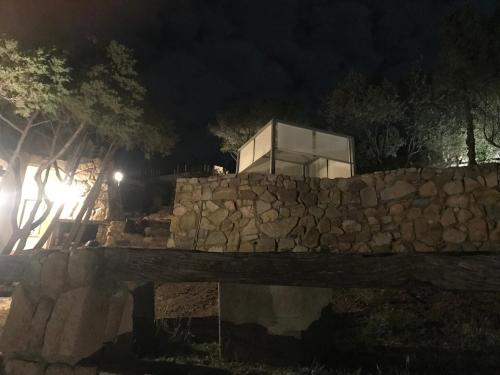 a building behind a stone wall at night at Villa Sardinia Seaview&SPApool in Villasimius