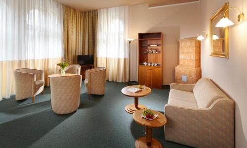 a hotel room with a couch and chairs and tables at Dr. Adler Spa & Kurhotel in Františkovy Lázně