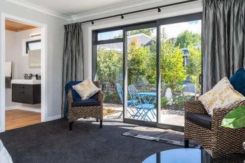 a living room with two chairs and a sliding glass door at Glenbervie Bed & Breakfast in Whangarei