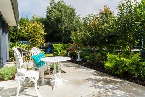 a patio with a table and chairs and flowers at Glenbervie Bed & Breakfast in Whangarei