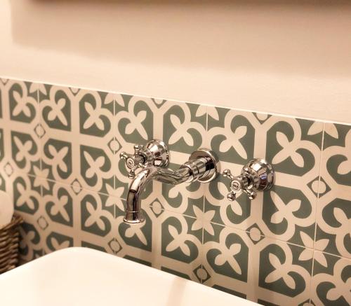 a bathroom sink with a faucet on a wall at The Houses of History - anno 1830 in Tihany