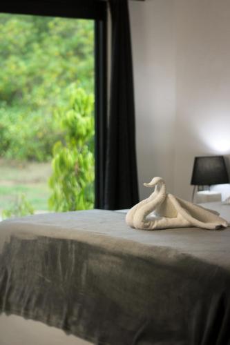 a stuffed animal sitting on a bed with a window at Show Pony Beach Resort and Suites in Las Lajas