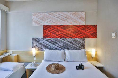 a bedroom with a bed with a hat on it at Ibis Maringa in Maringá