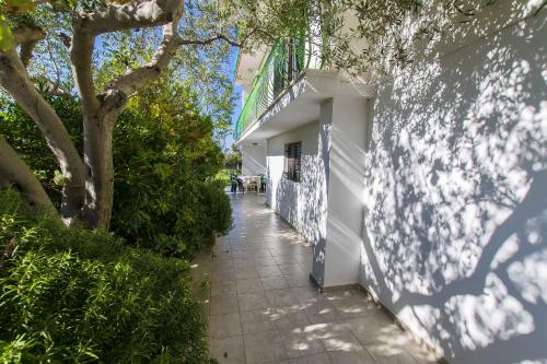 a sidewalk next to a white building with a tree at Apartments Milena in Rtina
