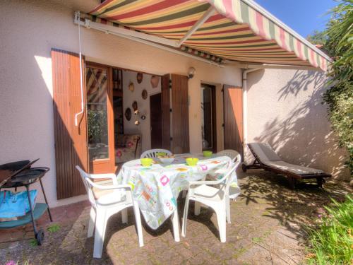 een patio met een tafel en stoelen en een parasol bij Holiday Home Juncades by Interhome in Seignosse