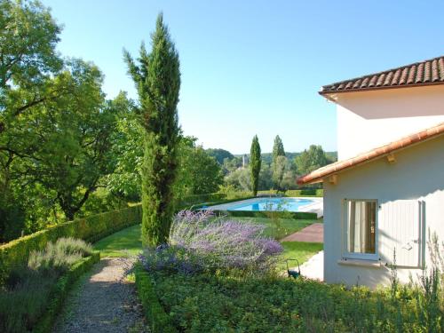 Holiday Home Lapeyriere by Interhome في Saint-Pantaléon: حديقة بها زهور أرجوانية بجوار منزل