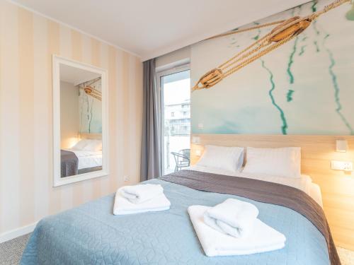 a bedroom with a blue bed with towels on it at Apartamenty Baltia Kołobrzeg - Bliżej Morza in Kołobrzeg
