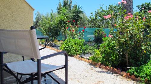 a chair in a garden with flowers and plants at Heliatoras Studios in Loutrópolis Thermís