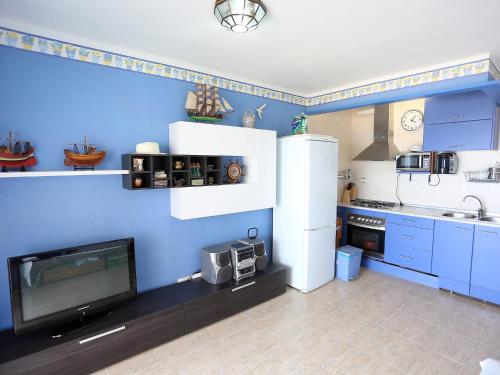 a kitchen with blue walls and a white refrigerator and a tv at Apartment MemLing-1 by Interhome in Vilafortuny